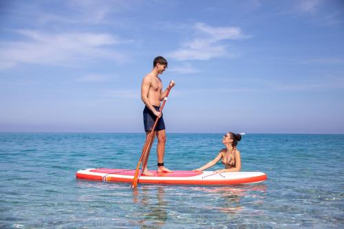 Ein Mann und eine Frau auf einem Paddelbrett im Ozean in der Unterkunft Park Oasi Resort in Zambrone