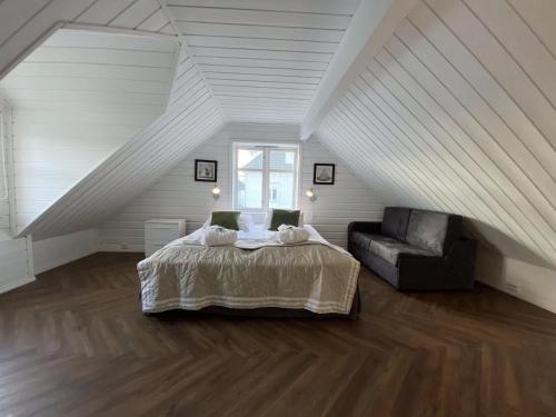 a bedroom with a bed and a couch in a attic at Enter Tromsø Luxury Apartments in Tromsø