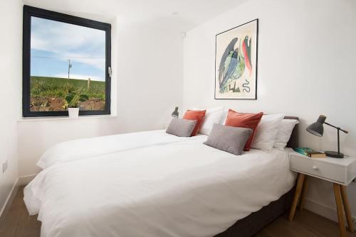 a white bedroom with a large bed and a window at 7 The Bay in Coldingham