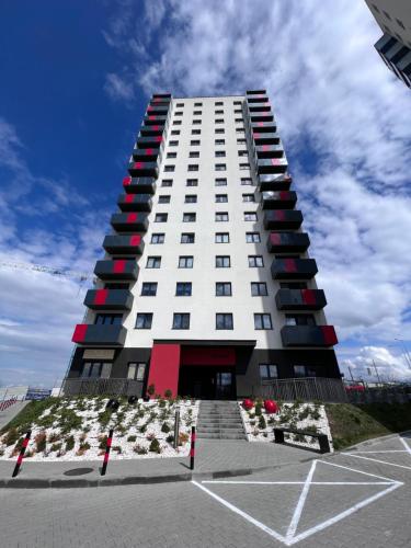 wysoki biały budynek z czerwonymi oknami i parkingiem w obiekcie Apartaments Baltycka 37 - Rzeszow w mieście Rzeszów