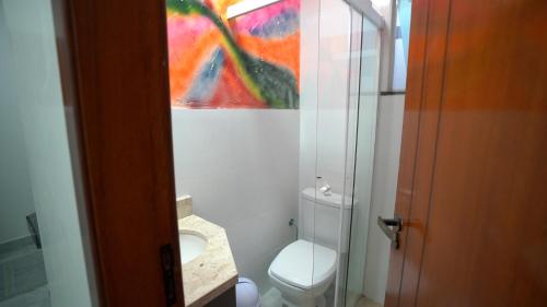 a bathroom with a toilet and a painting on the wall at Pousada Mirante do César in Bombinhas
