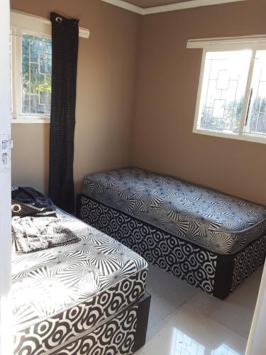 two beds and a ottoman in a room at Solitaires BnB in Durban