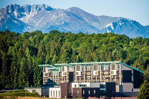 a large building with mountains in the background at Charming family condo in Silver Mountain in Poiana Brasov