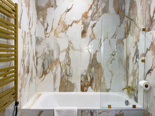 a bathroom with a tub and a marble wall at LUX Апартаменти MYFREEDOM поруч метро Театральна, Хрещатик in Kyiv