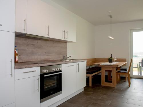 a kitchen with white cabinets and a wooden table at Hof am Horn - Fewos in der Natur in Laichingen