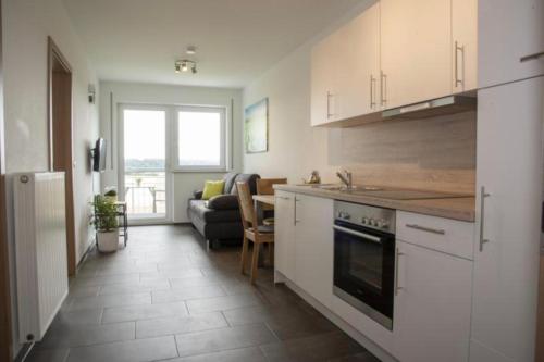 a kitchen with white cabinets and a living room at Hof am Horn - Fewos in der Natur in Laichingen