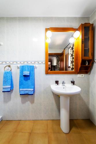 a bathroom with a sink and a mirror and blue towels at Casa Carmen, Montefrio in Montefrío