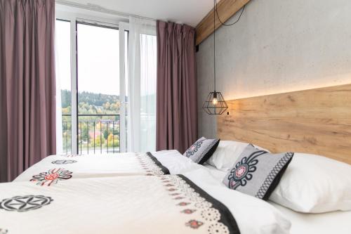 a bedroom with two beds and a large window at Apartament Bellavue w Czarnej Perle in Stronie Śląskie