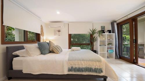 - une chambre avec un grand lit dans une pièce dotée de fenêtres dans l'établissement MacMasters Studio Retreat, à Macmasters Beach