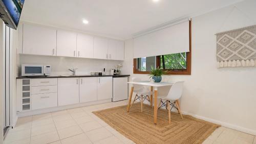 a kitchen with white cabinets and a table and chairs at MacMasters Studio Retreat in Macmasters Beach
