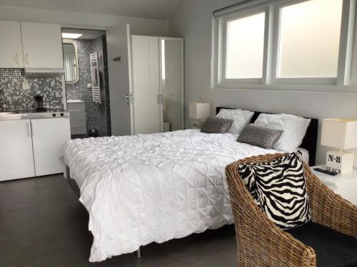 een slaapkamer met een wit bed en een keuken bij Studio Sunrise in Zandvoort