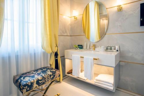 a bathroom with a sink and a mirror and a chair at Grand Hotel Principe Di Piemonte in Viareggio