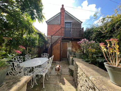a patio with a table and chairs and a dog at Bradford on Avon holiday cottage 4 bedroom near Bath in Bradford on Avon