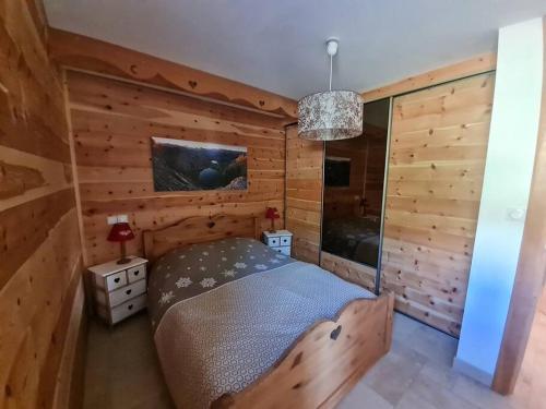um quarto com uma cama num quarto com paredes de madeira em Chalet La Cincia em Arvieux