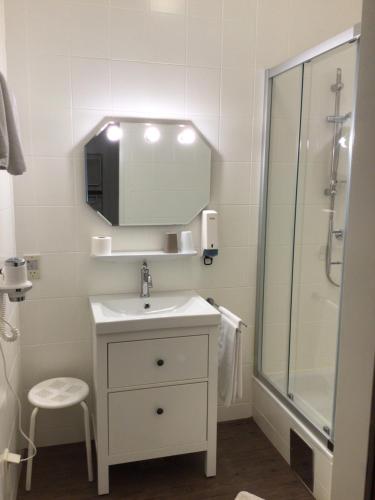 a white bathroom with a sink and a shower at Pension Claudia in Vösendorf