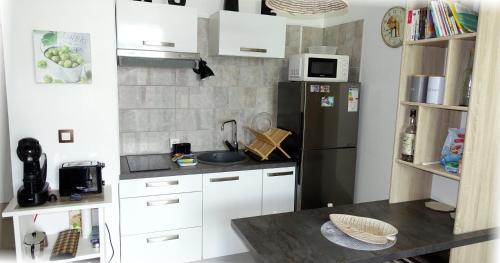 a kitchen with white cabinets and a black refrigerator at Studio Marina pointe du bout vue sur le port in Les Trois-Îlets