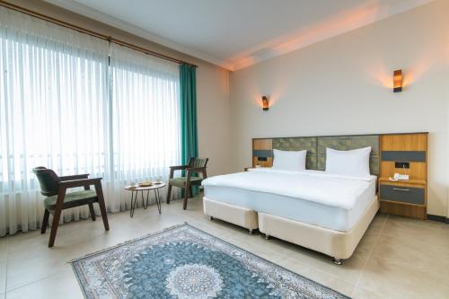 a bedroom with a large white bed and a table and chairs at Fevzi Hoca Otel in Trabzon