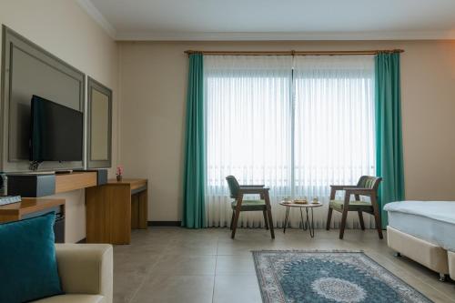 a living room with a bed and a tv and a couch at Fevzi Hoca Otel in Trabzon