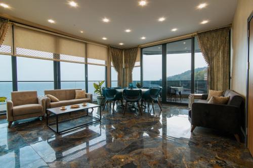 a living room with a table and chairs and windows at Fevzi Hoca Otel in Trabzon