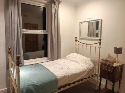 Habitación pequeña con cama y ventana en Victorian Terraced House in Salisbury; 3 bedrooms en Salisbury