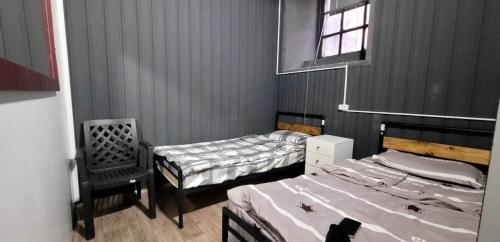 a bedroom with two beds and a chair and a window at Kiev hostel in Tbilisi City