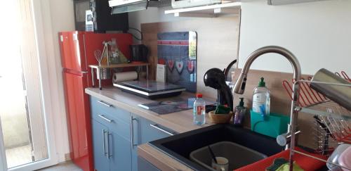 La cuisine est équipée d'un évier et d'un réfrigérateur rouge. dans l'établissement Joli appartement vue sur mer, à Cannes