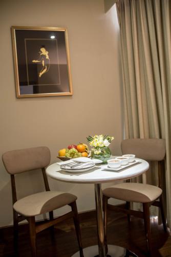 a white table with two chairs and a bowl of fruit at HOTEL dGATES in Lahore