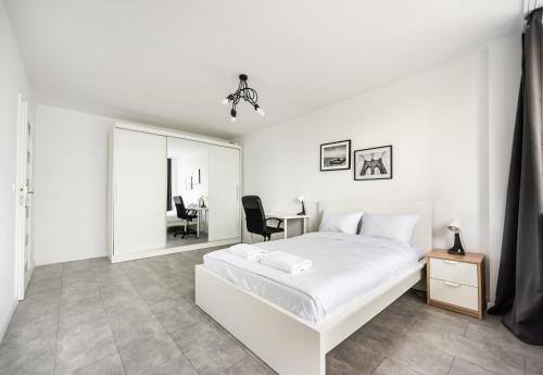 a white bedroom with a white bed and a desk at Saska Kępa Comfort Apartment in Warsaw