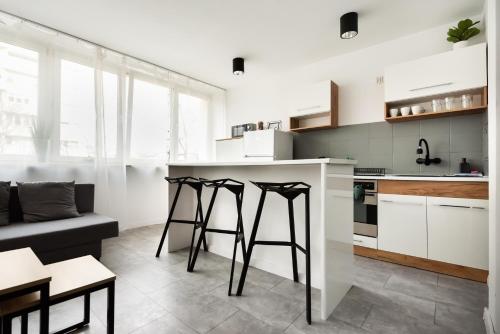 a kitchen with white cabinets and black stools at Saska Kępa Comfort Apartment in Warsaw