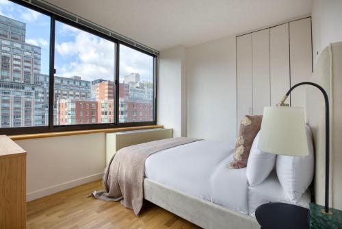 a bedroom with a bed and a large window at UES 2br w elevator doorman nr transportation NYC-1297 in New York