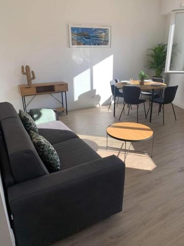 un salon avec un canapé noir et une table dans l'établissement Duplex au cœur du village de Cassis, à Cassis