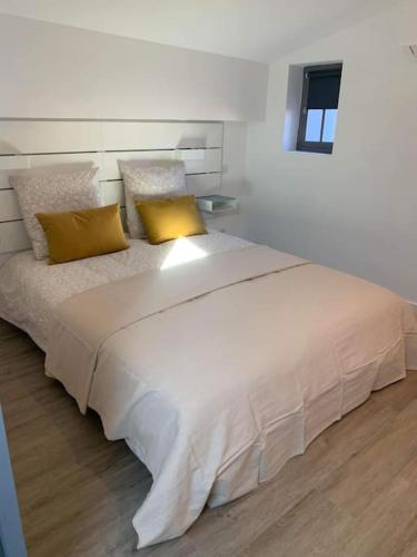 - un grand lit blanc avec 2 oreillers jaunes dans l'établissement Duplex au cœur du village de Cassis, à Cassis