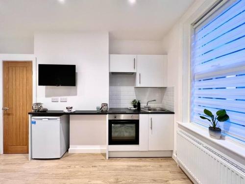 een keuken met witte kasten, een wastafel en een raam bij The Beach House, The Kove, Bournemouth Beach in Bournemouth