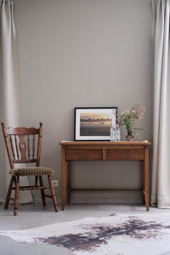 a wooden desk with a picture on it next to a chair at Hotel Pernigele in Jelgavkrasti