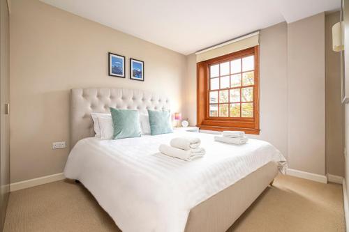 a bedroom with a large white bed with towels on it at Peaceful Putney apartment by UnderTheDoormat in London