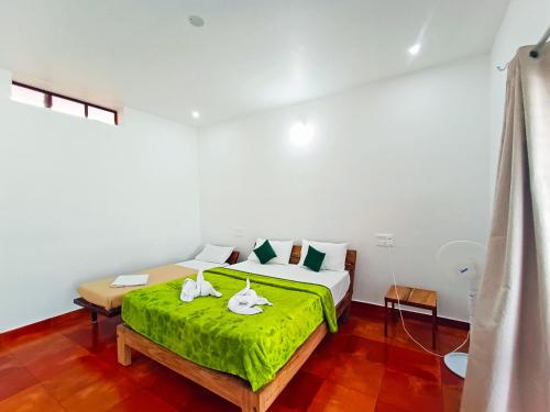 a bedroom with a bed with a green blanket at STAYMAKER Sereno Resort in Sakleshpur
