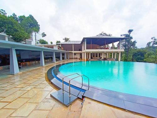 a large swimming pool in front of a building at STAYMAKER Sereno Resort in Sakleshpur
