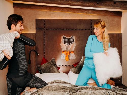 a man and a woman sitting on a bed at Boutique Hotel Haidachhof superior in Fügen