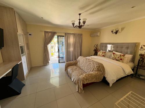 a large bedroom with a bed and a chair at Blue Diamond Lodge in Springbok