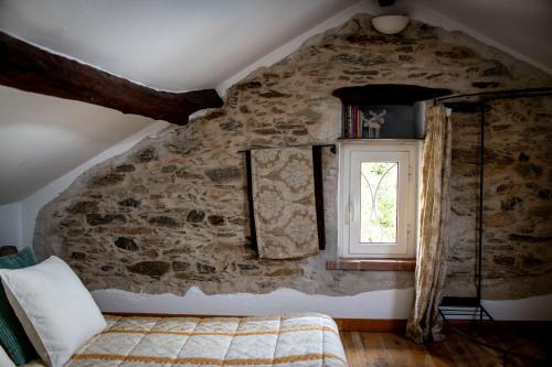 ein Schlafzimmer mit einer Steinmauer und einem Fenster in der Unterkunft Pin de stèlle in San Martino