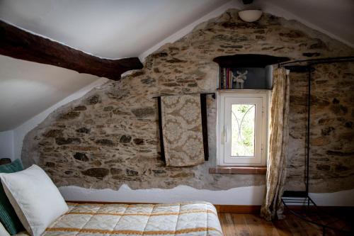 a bedroom with a stone wall and a window at Pin de stèlle in San Martino