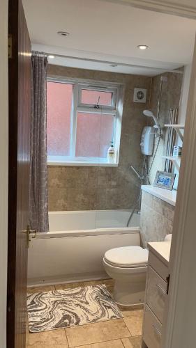 a bathroom with a tub and a toilet and a window at Gables in Hither Green