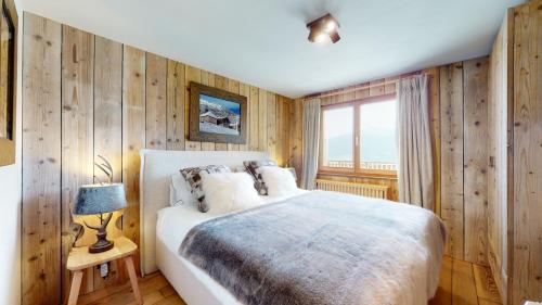 um quarto com uma cama com paredes de madeira e uma janela em Arnold COCOONING & VIEW chalet 12 personnes Les Masses em Les Collons