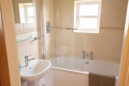 ein Badezimmer mit einer Badewanne und einem Waschbecken in der Unterkunft Grange Farm Cottages in Wressell