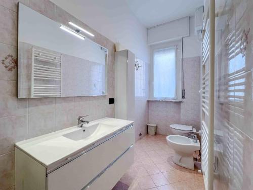 La salle de bains blanche est pourvue d'un lavabo et de toilettes. dans l'établissement Appartamento vicino al Porto, à Varazze