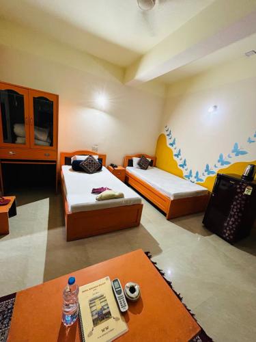 a room with two beds and a table in it at Hotel Siddarth Palace in Mangaldai