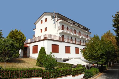 un gran edificio blanco con balcón y árboles en Hotel Del Duca, en Montedinove