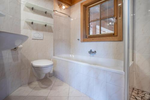 a bathroom with a tub and a toilet and a sink at Chalet Schneespaß in Königsleiten