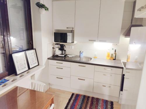 a white kitchen with a sink and a microwave at Studio Porin Karhu, home away home in Pori city center, free parking in Pori