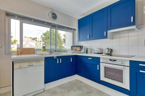 une cuisine bleue avec des appareils électroménagers blancs et des armoires bleues dans l'établissement Vue mer La Baule : L'escale Bauloise, à La Baule